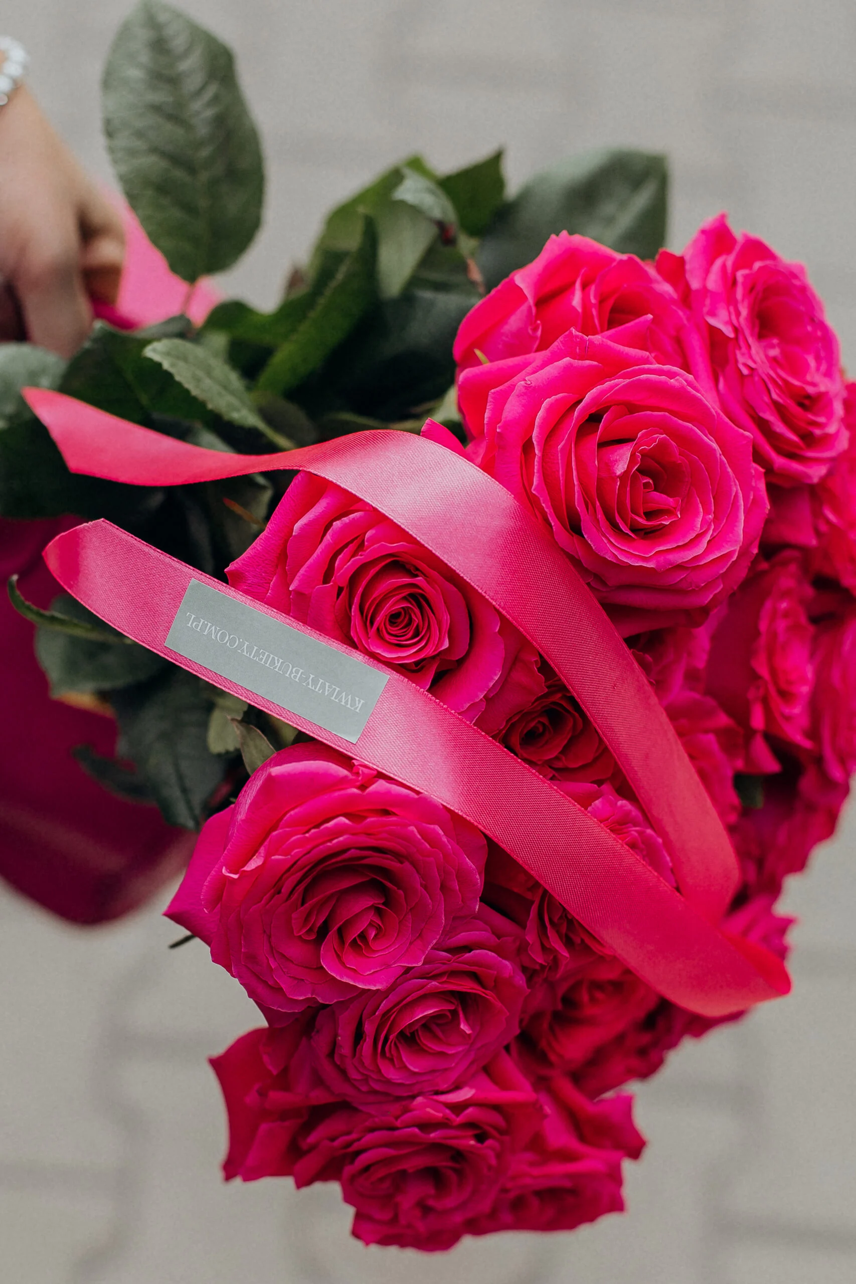 Bukiet róż z intensywnie różowymi różami przewiązany satynową wstążką