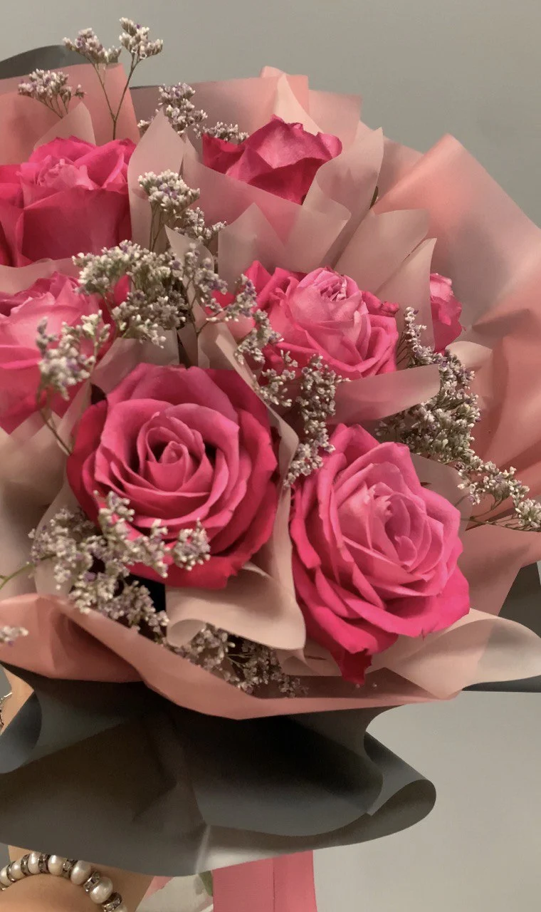 Bukiet róż z żywymi różowymi różami i lekką gipsówką w papierze ozdobnym