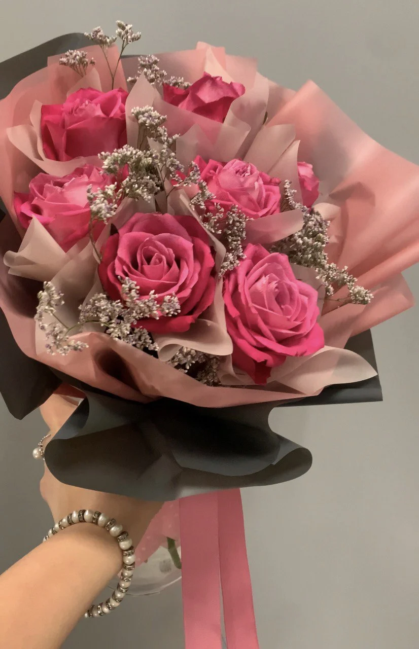 Bukiet z różowych róż i drobnych białych kwiatów w ozdobnym opakowaniu