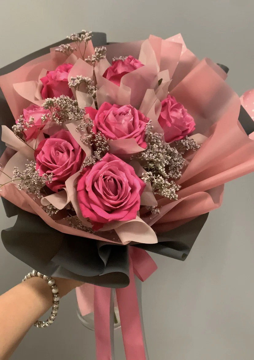 Bukiet róż z intensywnie różowymi różami i delikatną gipsówką w eleganckim papierze