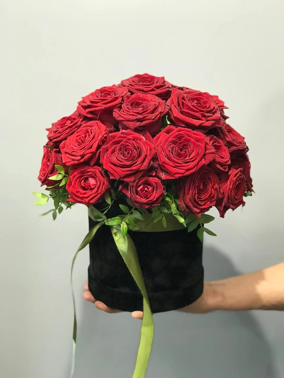 Flower box z czerwonymi różami w czarnym pudełku przewiązanym zieloną tasiemką