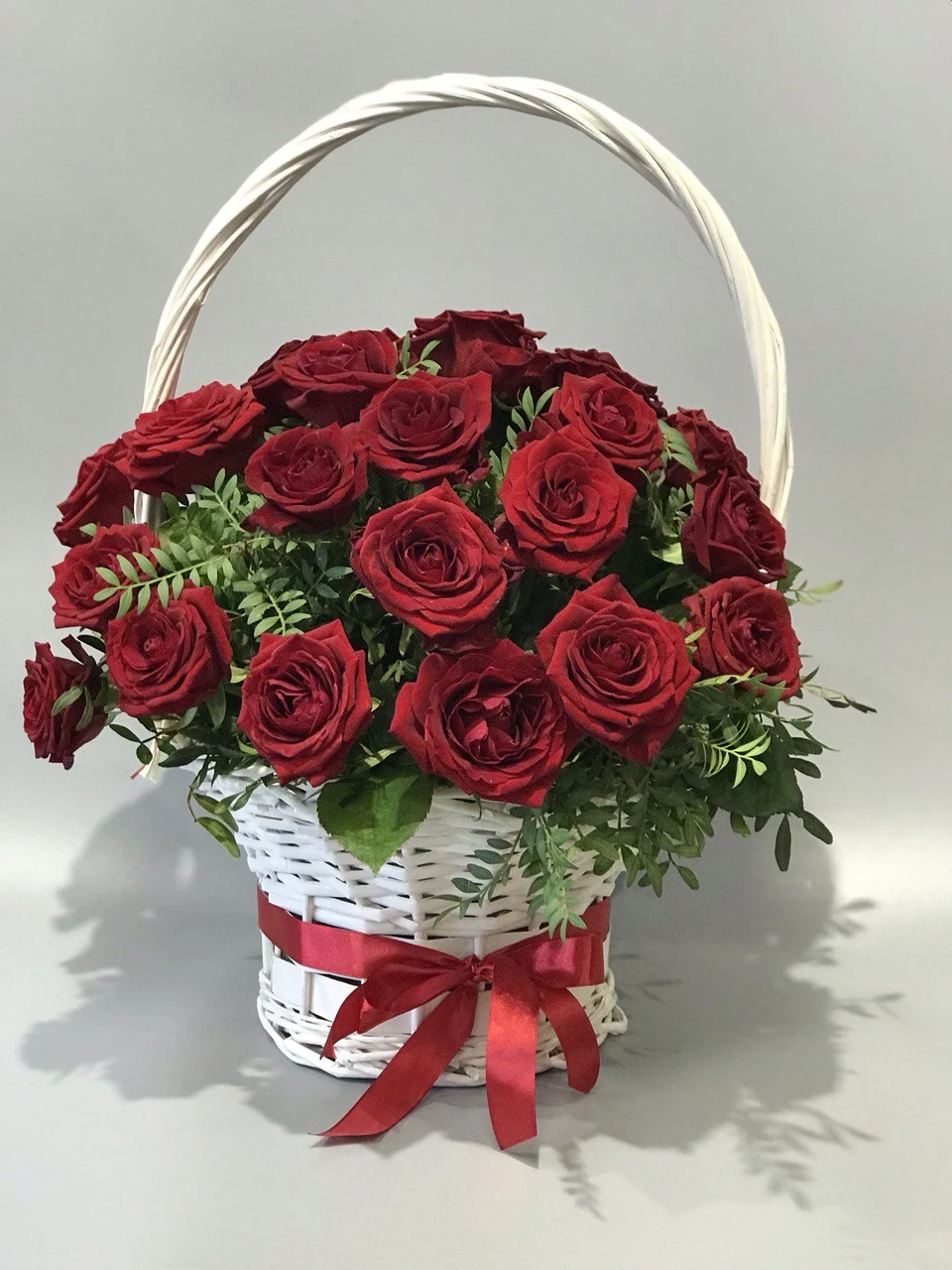 Bukiet róż w białym koszyku z czerwonymi różami i zielenią