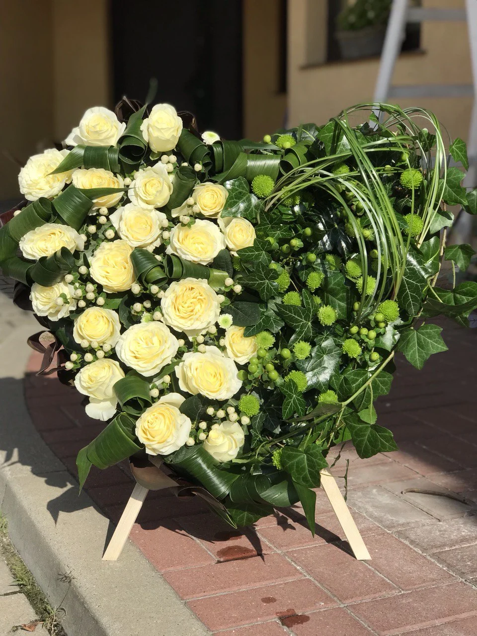 Bukiet róż pogrzebowy w formie serca z białymi akcentami i liśćmi