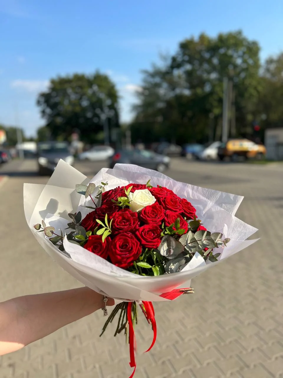 Elegancki bukiet czerwonych róż z akcentem w postaci jednej białej róży