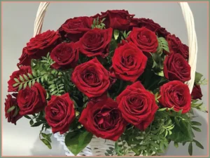 Czerwone róże w eleganckim białym koszu z wysokim uchwytem.