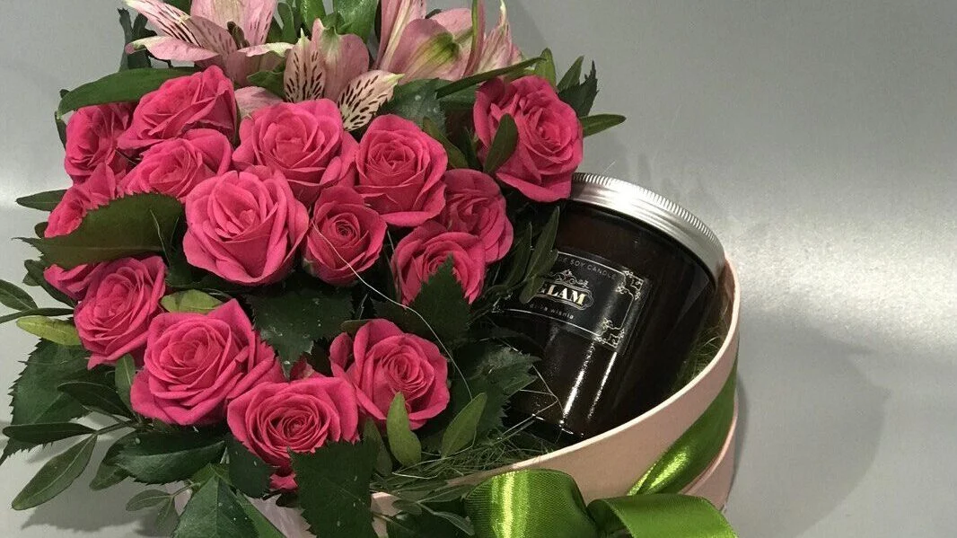 Różowe róże z aromatyczną świecą w ozdobnym pudełku.