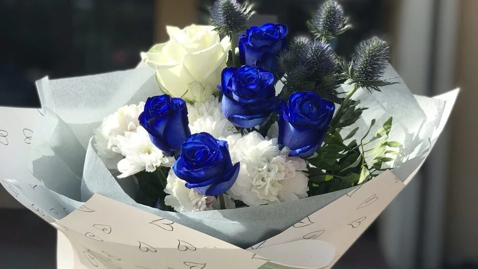 Bukiet z niebieskimi i białymi różami oraz innymi kwiatami.