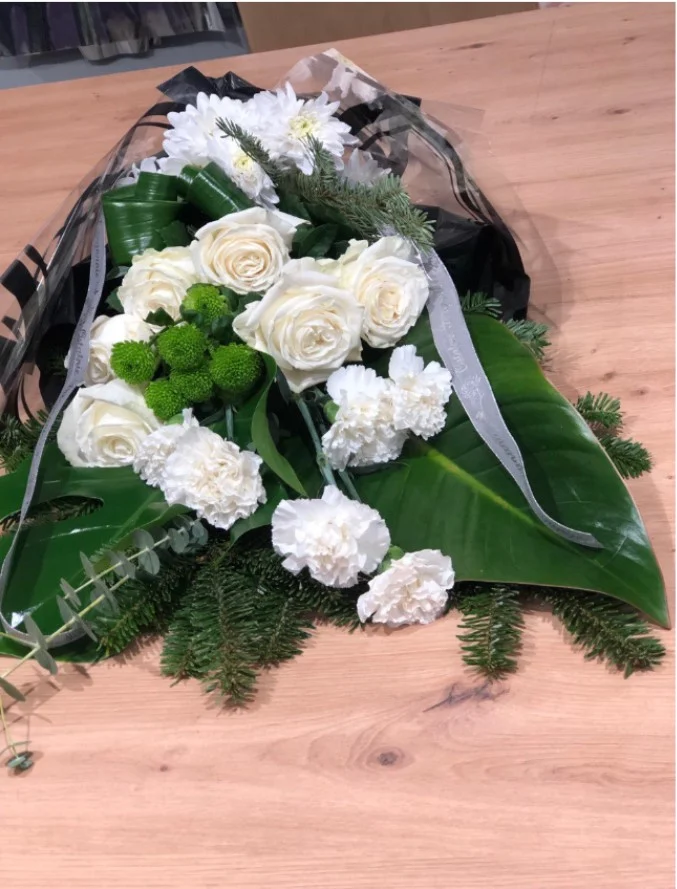 Bukiet pogrzebowy z białych róż i goździków z zielonymi dodatkami