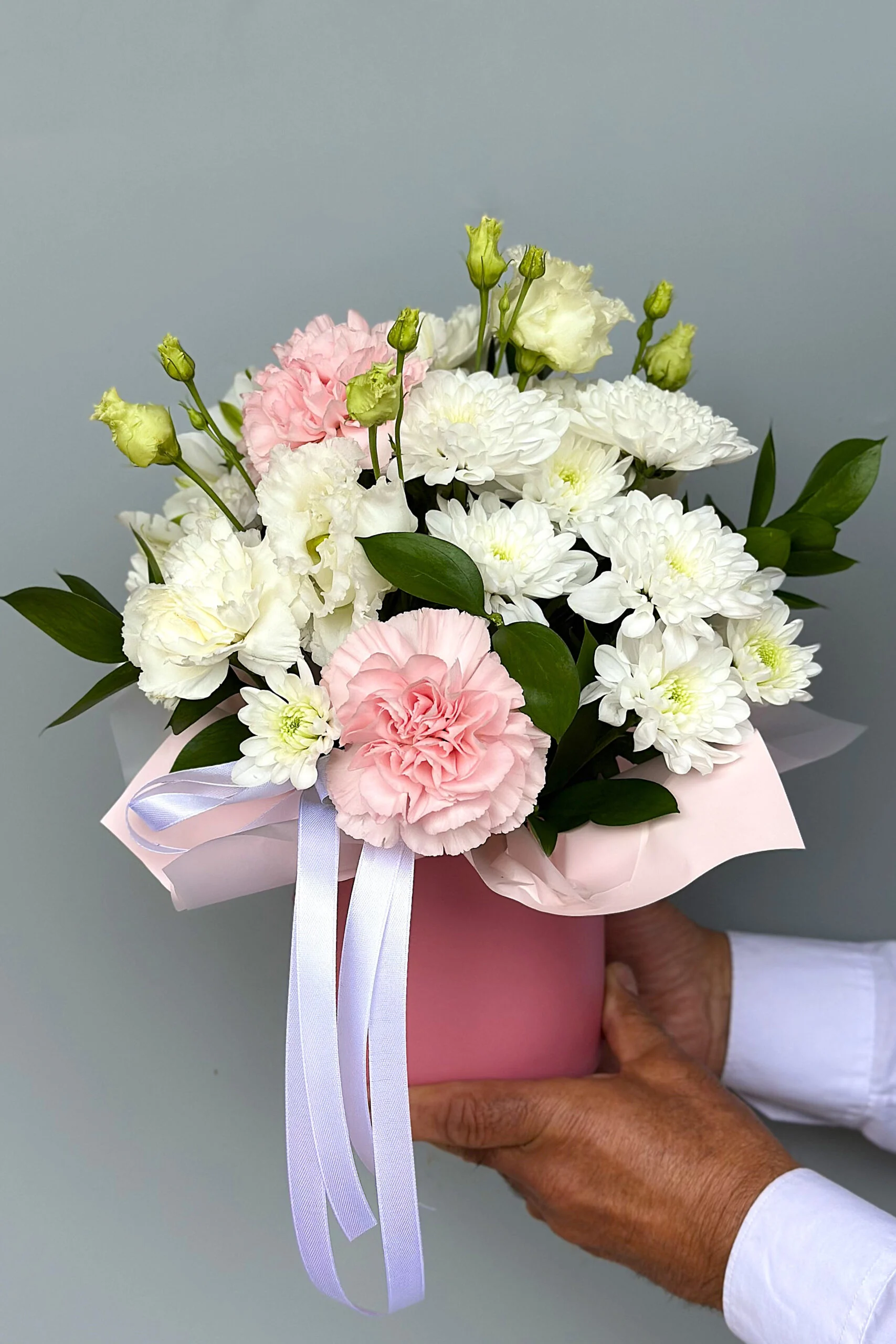 Uroczy flower box róże z jasnymi kwiatami i wstążką