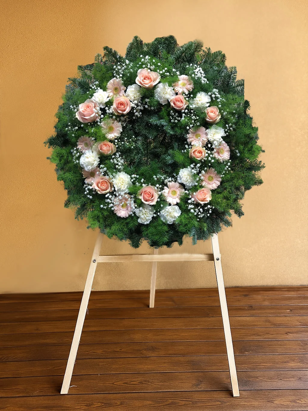 Wieniec pogrzebowy z różowymi i białymi różami na stojaku