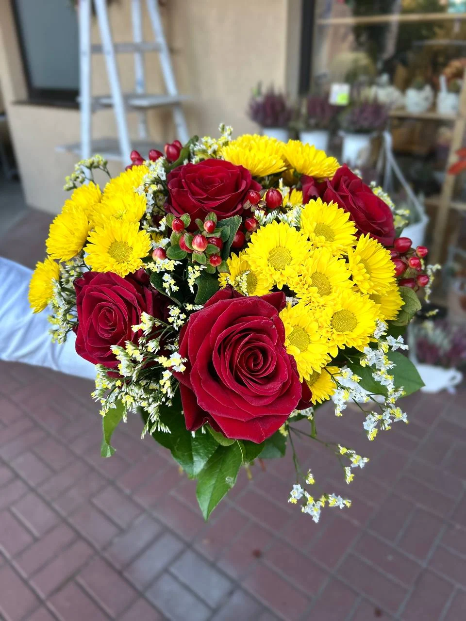 Radosny bukiet czerwonej róży z żółtymi margaretkami i hiperikum